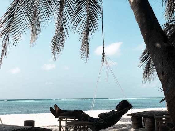 a person laying in a hammock on the beach