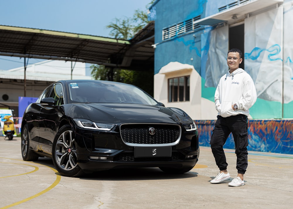 a man standing next to a black car