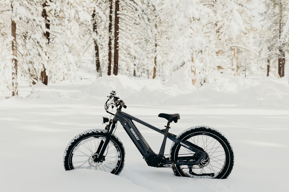a bicycle parked in the snow in a forest