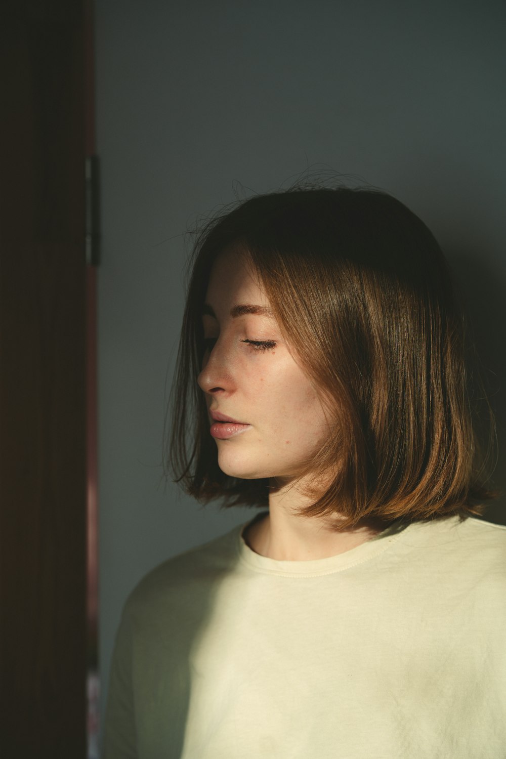 a woman with her eyes closed standing in front of a door