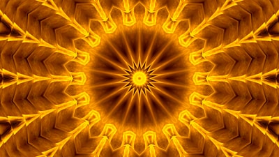 An intricate mandala pattern with a radial symmetry, featuring multiple triangular layers emanating from a central starburst design. The image is filled with rich golden hues, creating a sense of depth and texture. The repetitive arrangement of shapes gives a kaleidoscopic effect.
