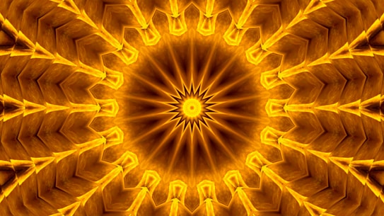 An intricate mandala pattern with a radial symmetry, featuring multiple triangular layers emanating from a central starburst design. The image is filled with rich golden hues, creating a sense of depth and texture. The repetitive arrangement of shapes gives a kaleidoscopic effect.