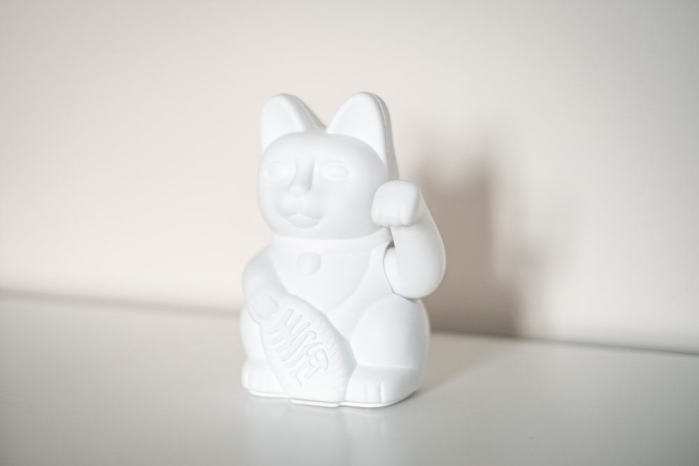a white cat figurine sitting on top of a table