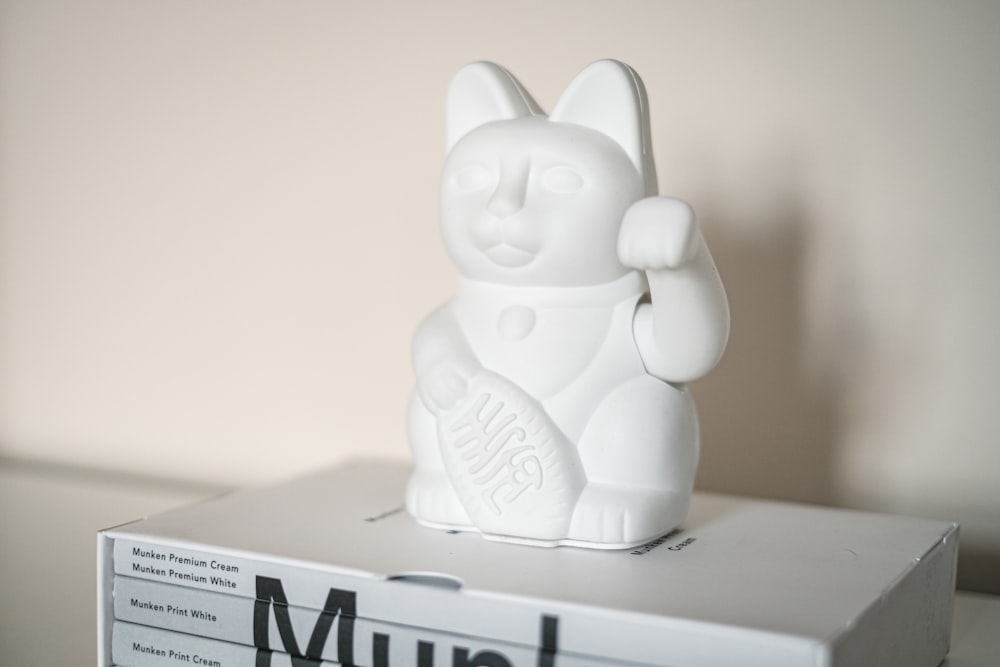 a white cat figurine sitting on top of a box