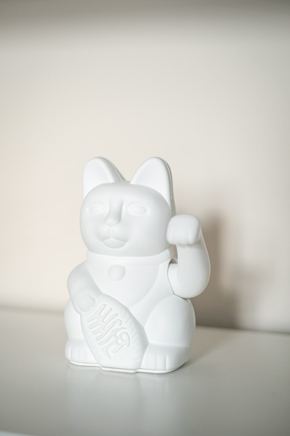 a white cat figurine sitting on top of a table