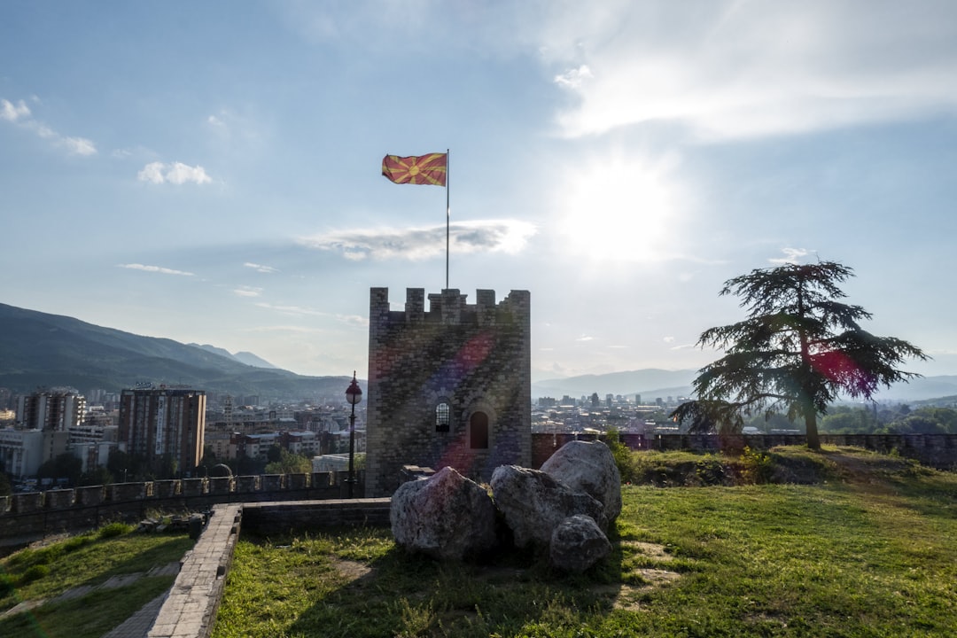 a castle with a flag on top of it, The flag of North Macedonia flying over the capital of Skopje.