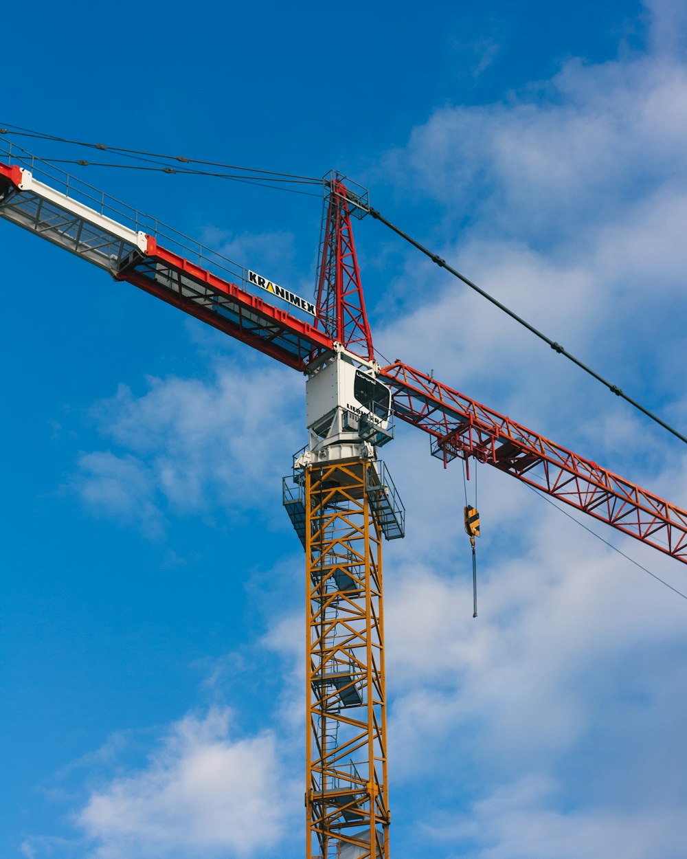 a red and white tower crane against a blue sky