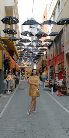 A model walking through a mustard yellow painted alleyway, showcasing a flowing dress from the Chocolate Sunshine Boutique collection.