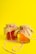 Two glass jars filled with a light amber liquid are topped with rustic burlap covers, tied with red and white striped twine. These jars are set against a bright yellow background, and one jar has a loose length of twine trailing across the surface.