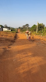 A group of villagers working together on a community road construction project under clear skies.
