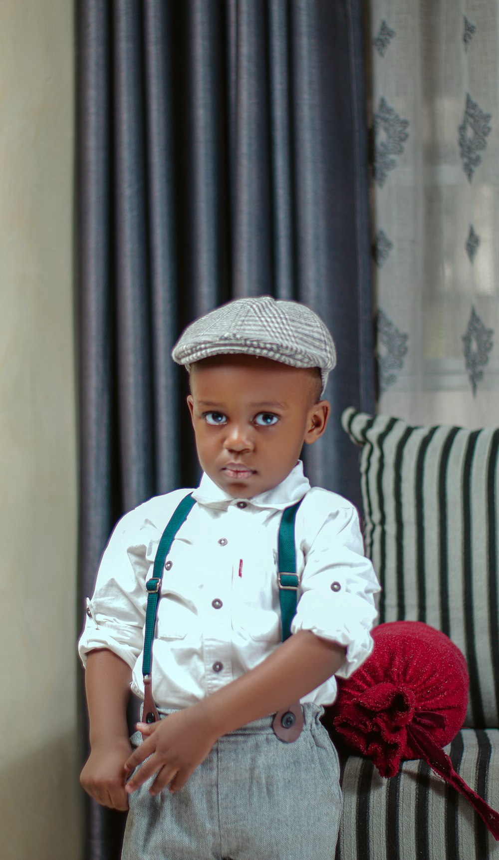 a young boy wearing a hat and suspenders