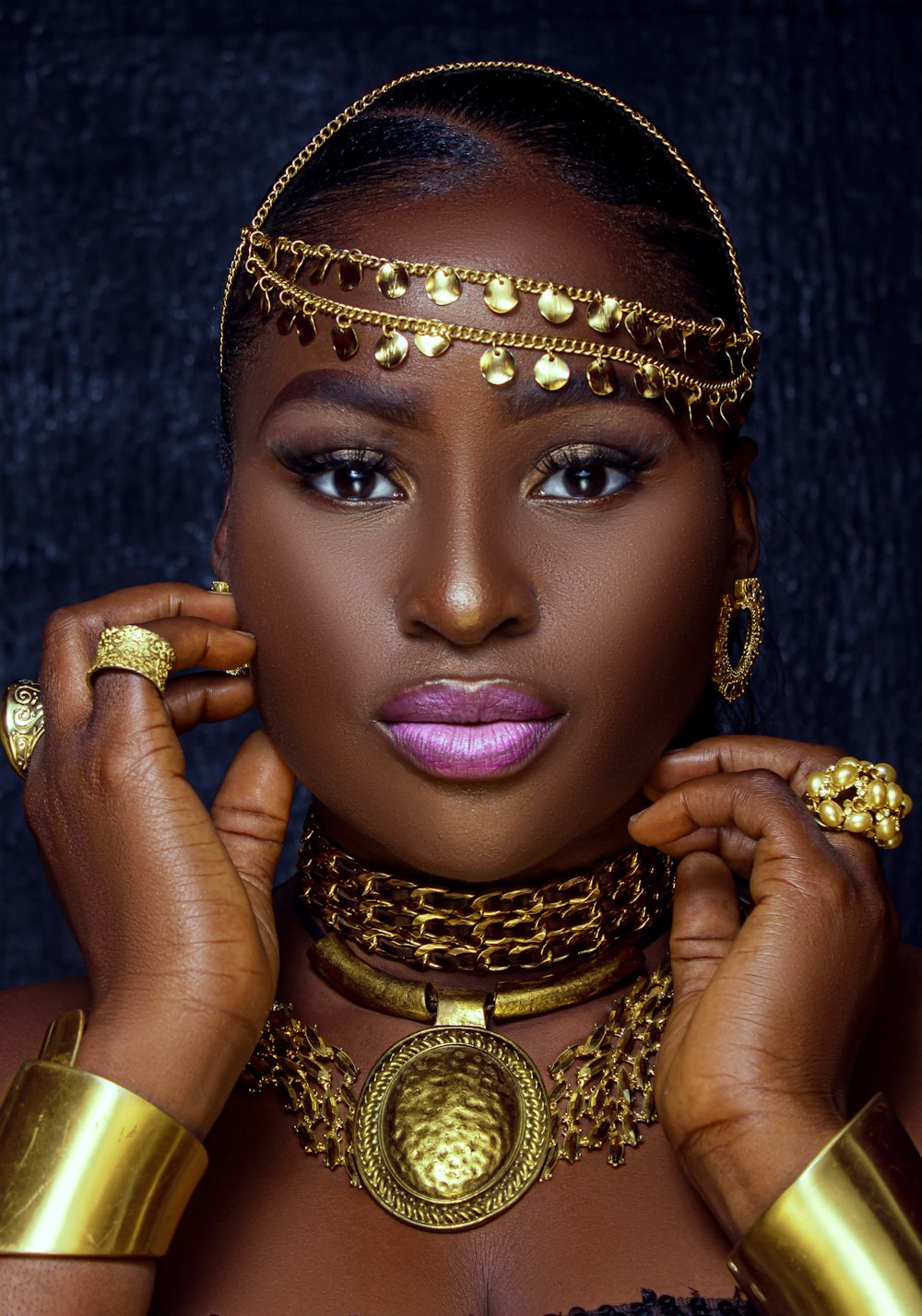 a woman wearing gold jewelry and a head piece