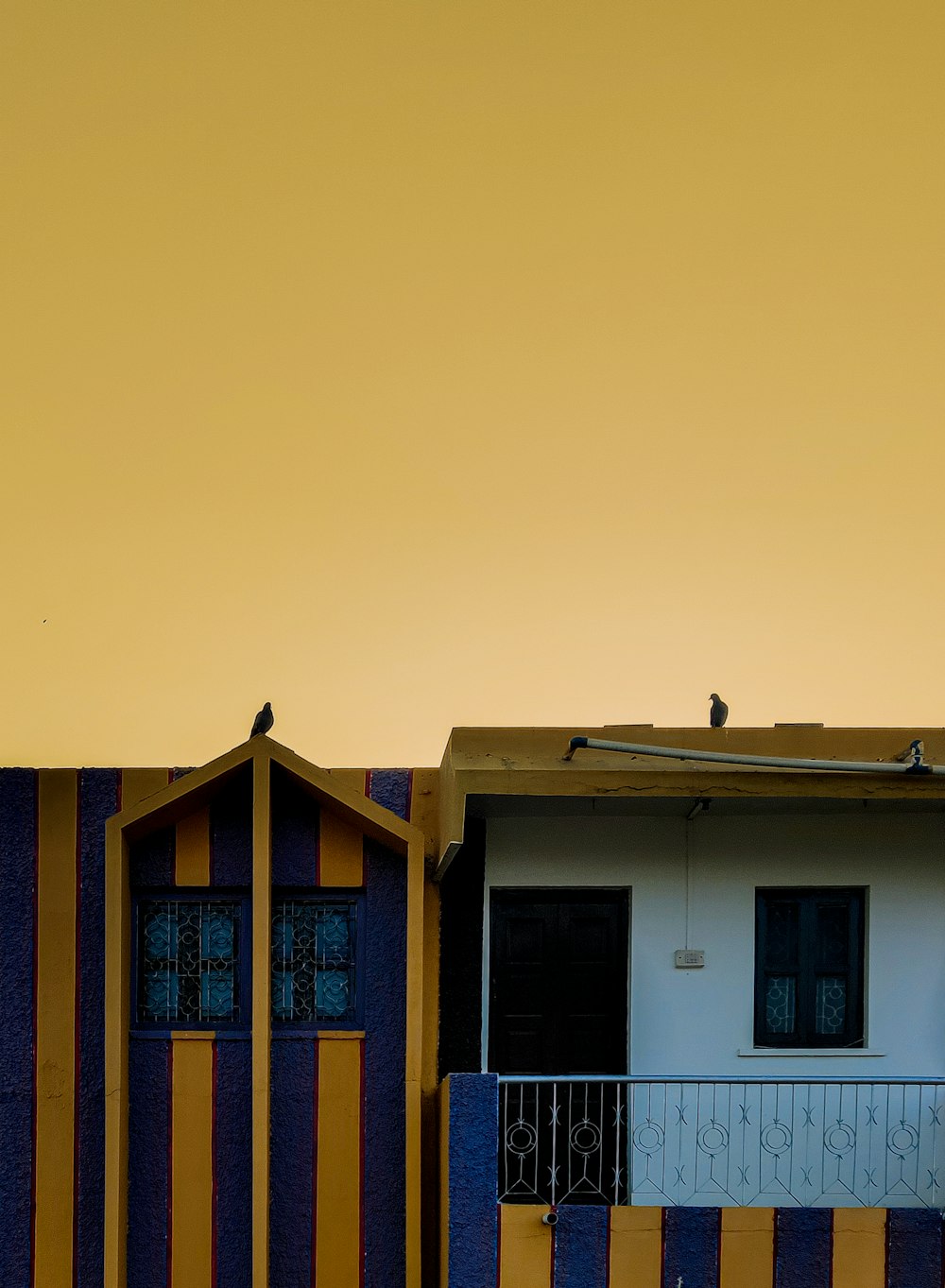 a yellow and blue building with a bird sitting on top of it