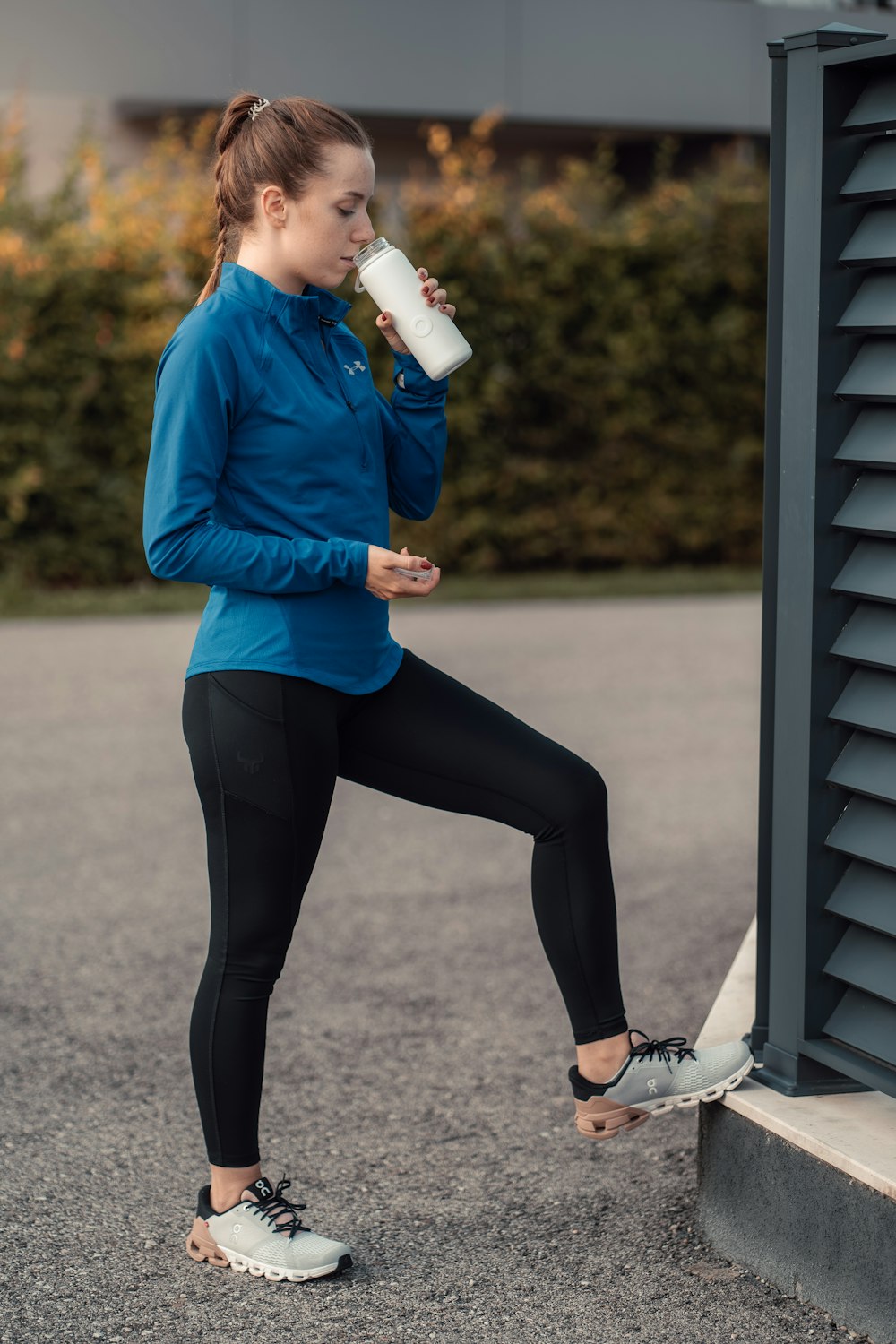 a woman in a blue jacket drinking from a cup