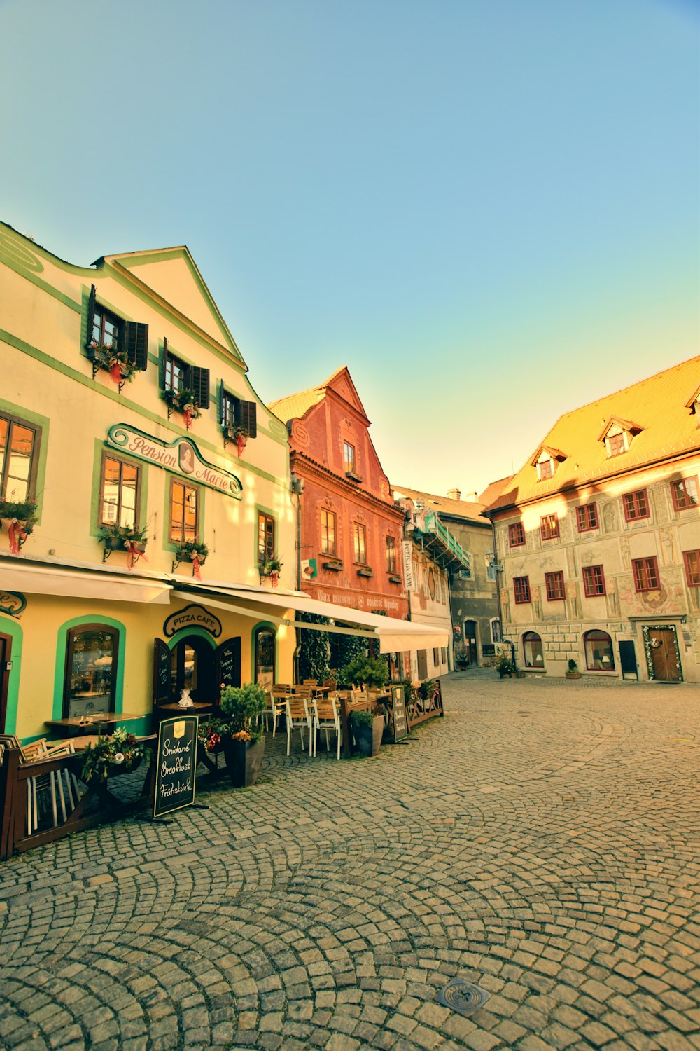 a cobblestone street lined with buildings and tables