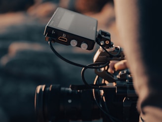 a person holding a camera with a cell phone attached to it