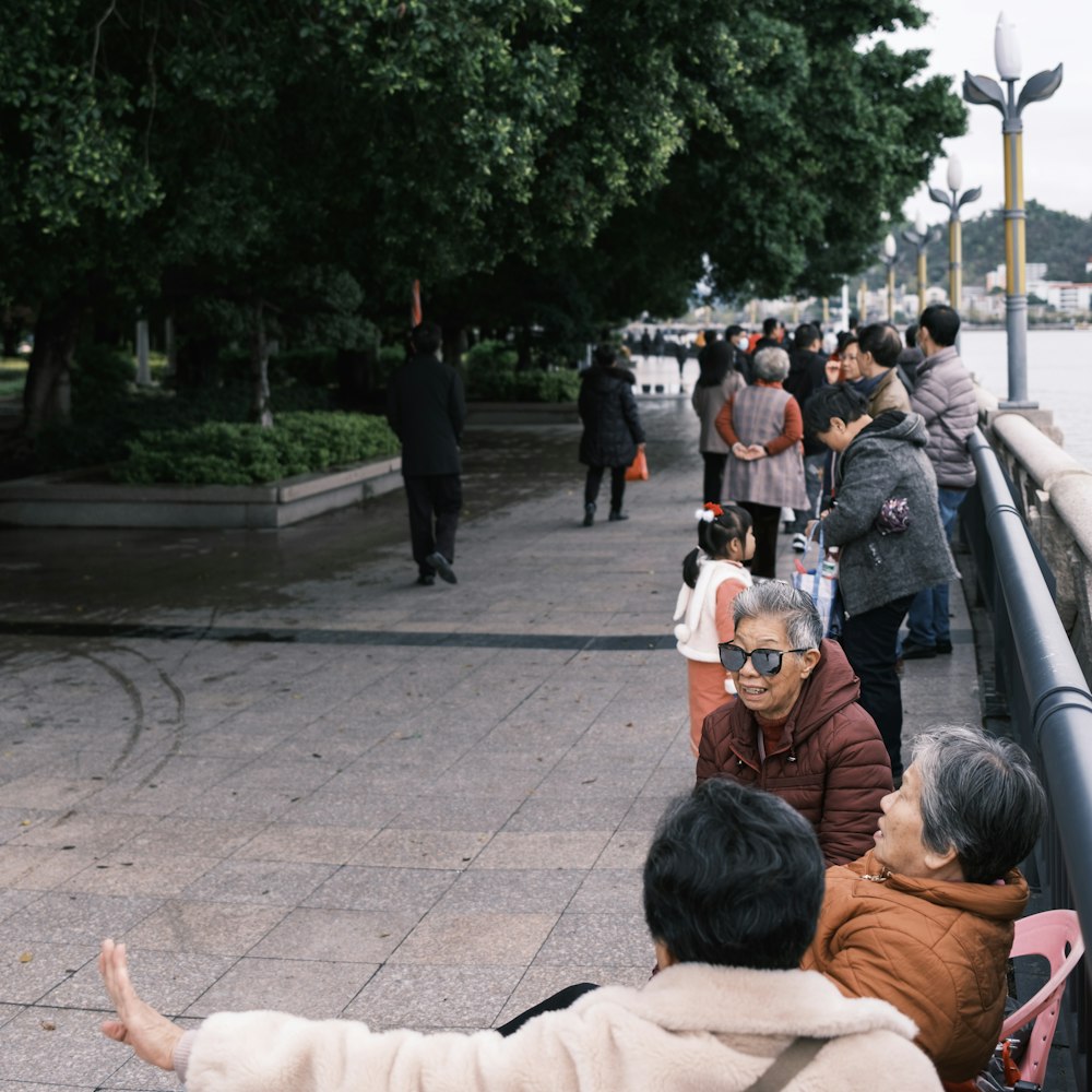 a group of people standing on a sidewalk next to a body of water