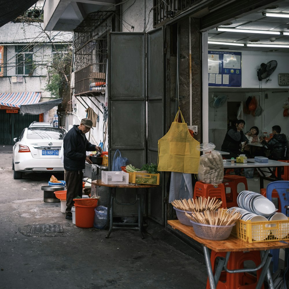 a man standing in front of a store next to a white car