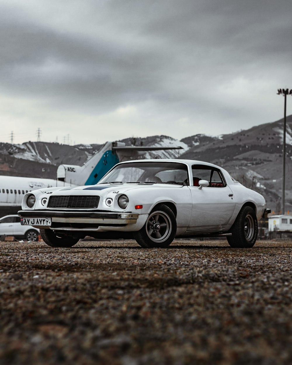 a white car parked in front of an airplane