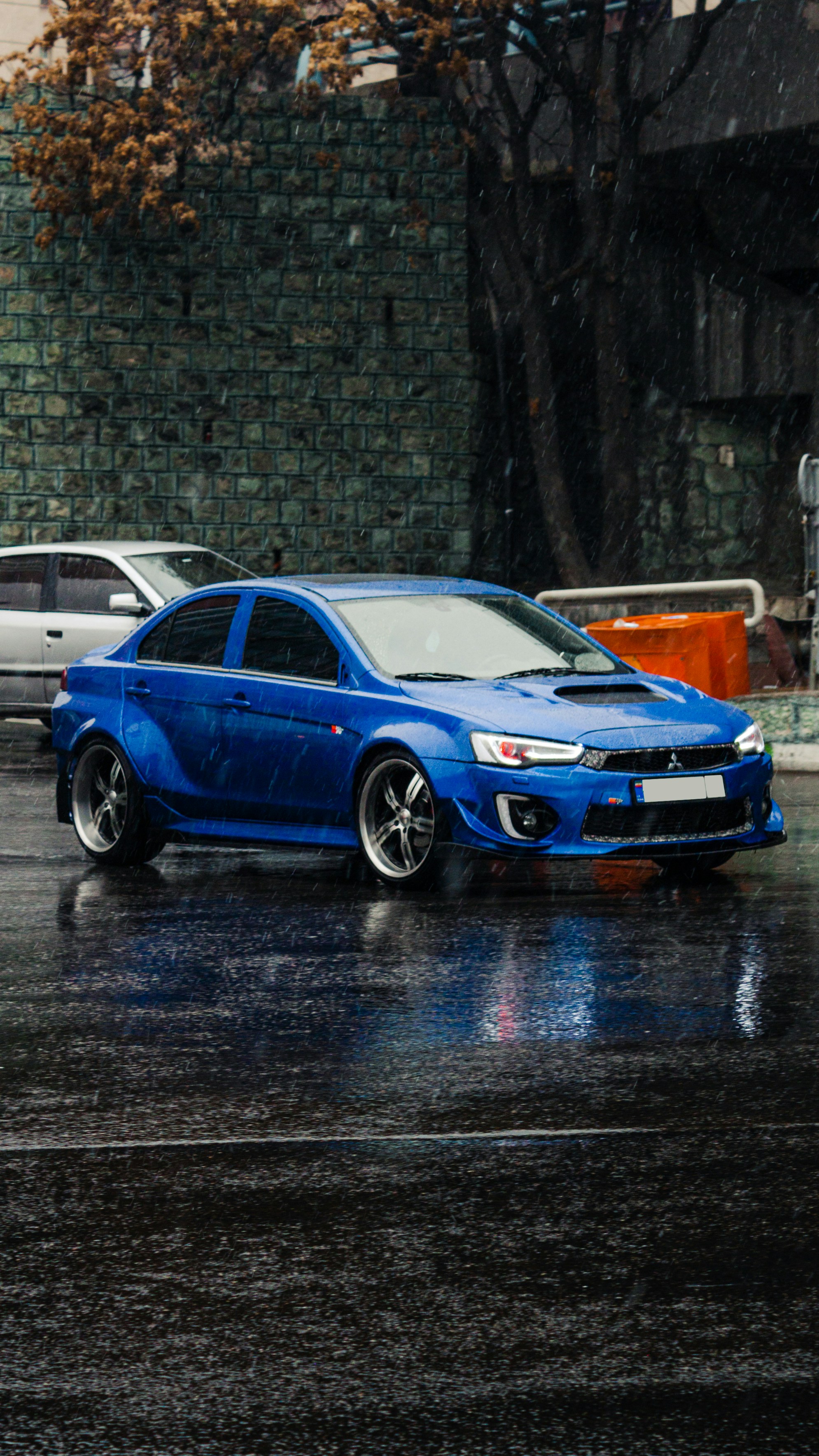 a blue car parked on a wet street