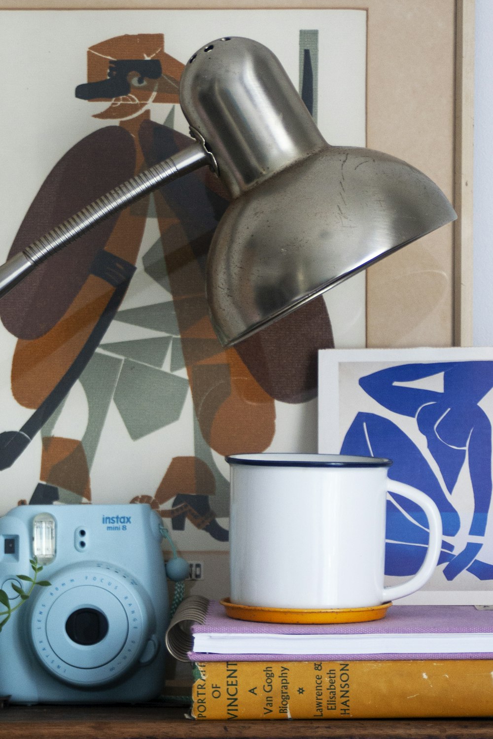 a table with a camera, a cup, and a lamp on it