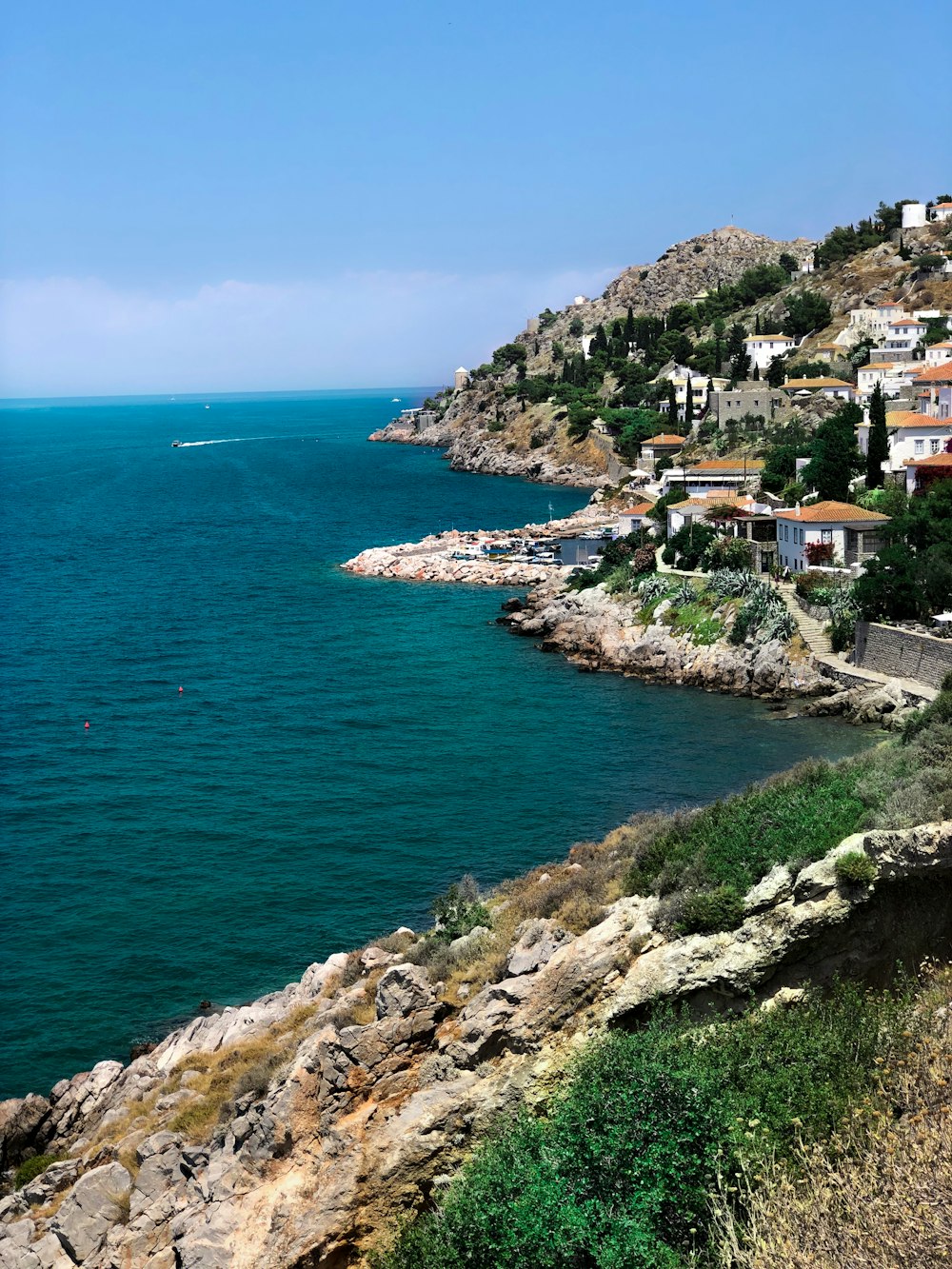 a body of water with houses on a hill in the background