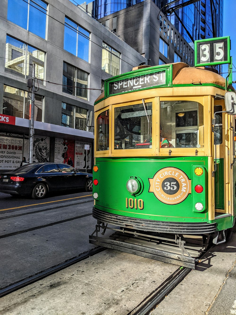 a green and yellow trolley on a city street