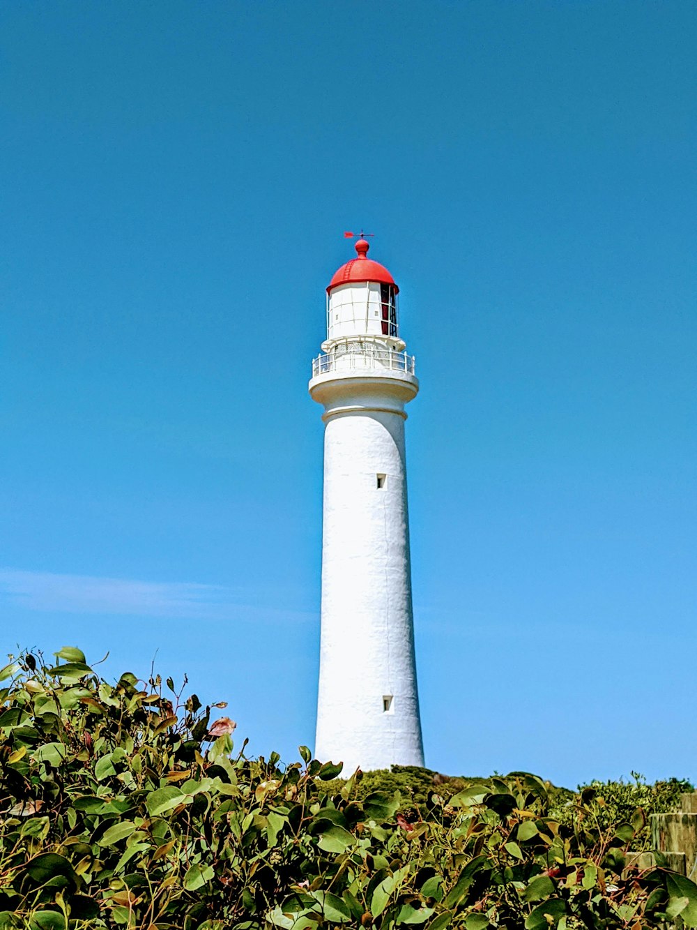 a white lighthouse with a red top on a clear day