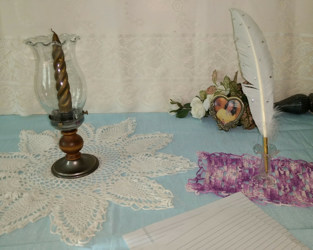 a table topped with a feather and a vase filled with flowers