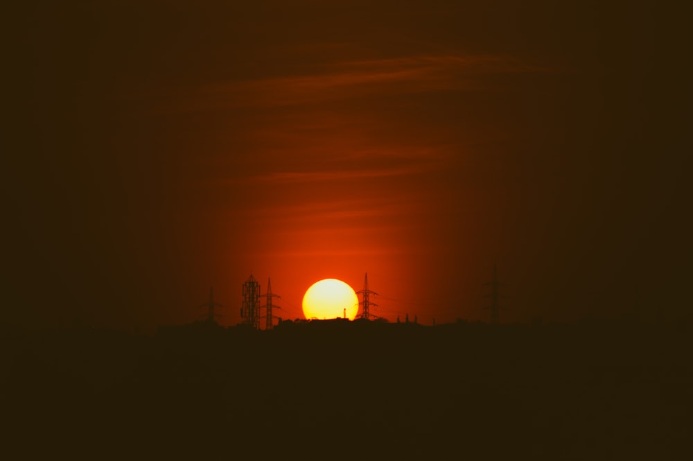 the sun is setting over a field with power lines