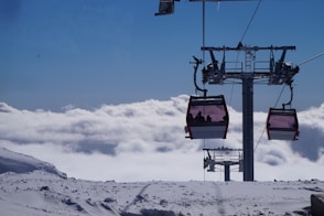 a ski lift with two people on it above the clouds