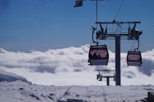 a ski lift with two people on it above the clouds