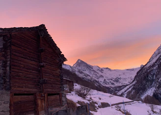 Artistic wood burning piece showing a rustic cabin surrounded by mountains at sunset.