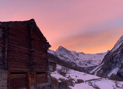 Artistic wood burning piece showing a rustic cabin surrounded by mountains at sunset.