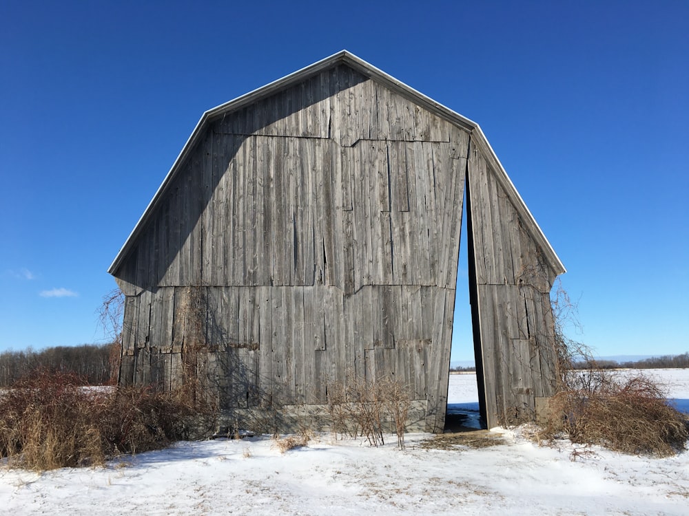 a barn in the middle of a snowy field