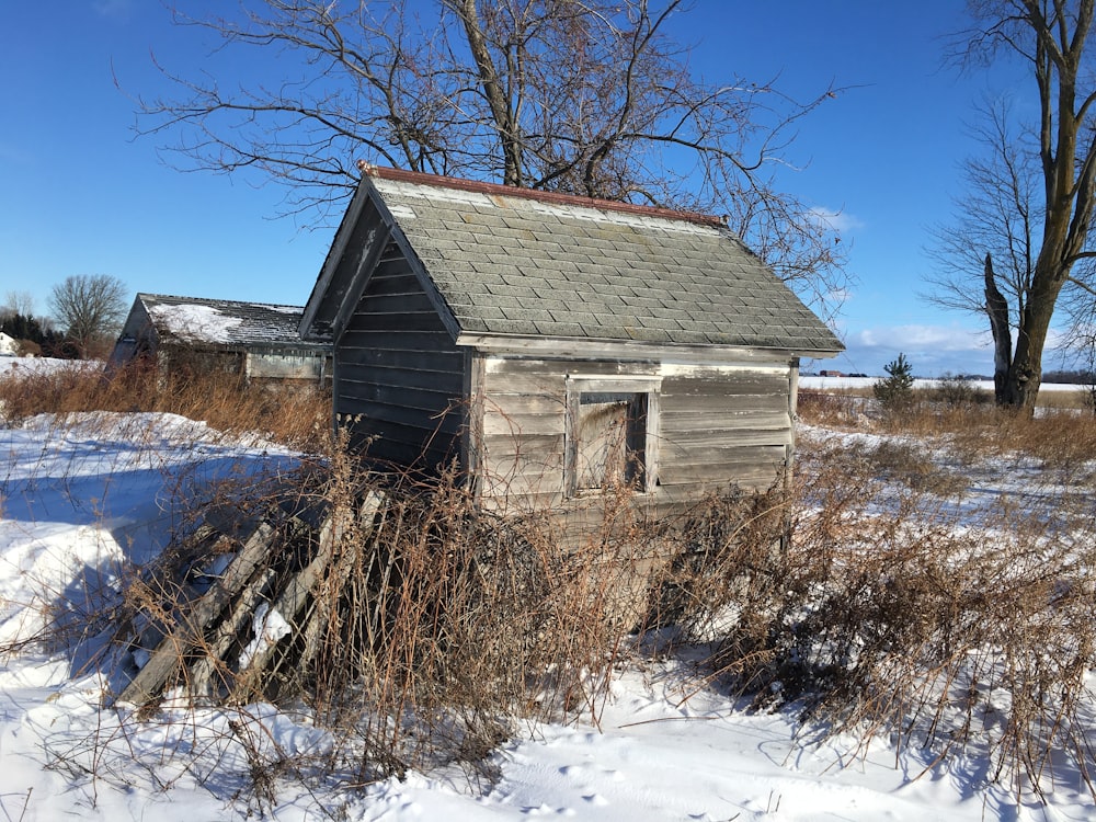 an old outhouse in the middle of a snowy field