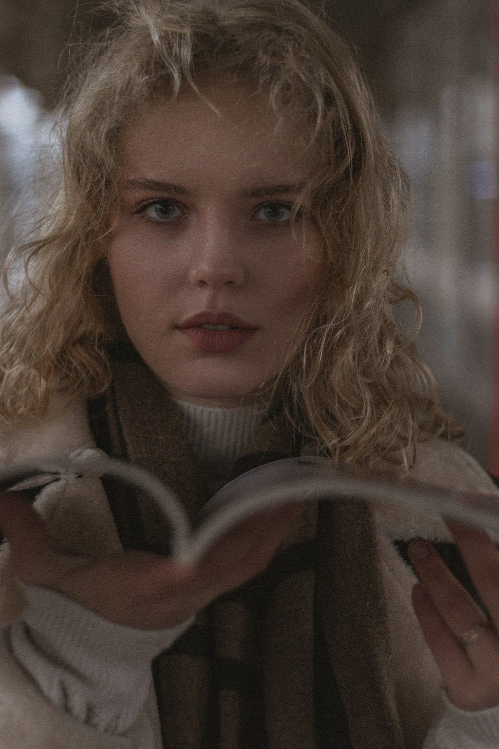 a woman is reading a book while wearing a coat