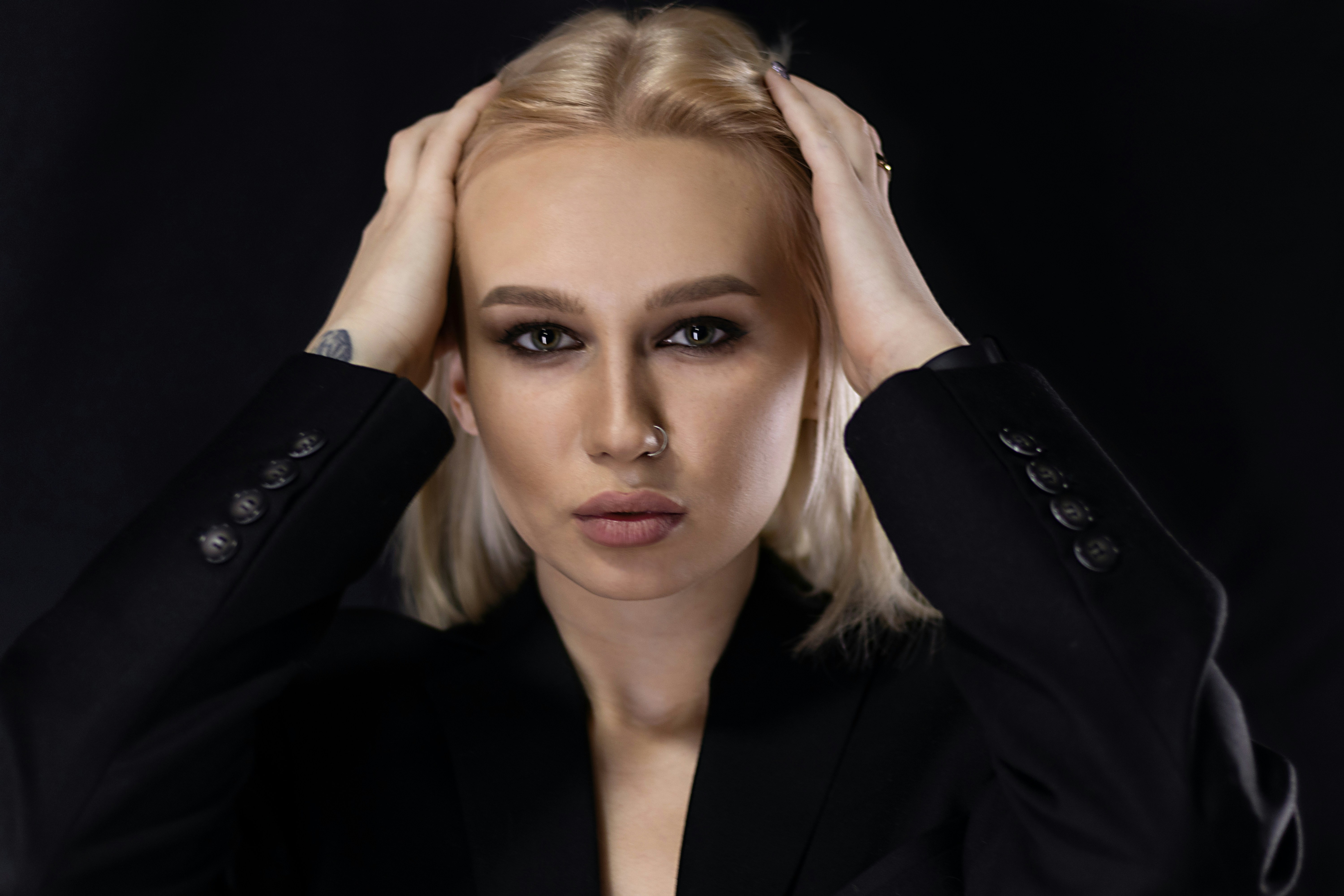 a woman in a black suit holding her head