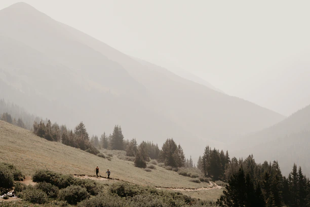 Couple hiking on a scenic mountain trail surrounded by lush greenery.