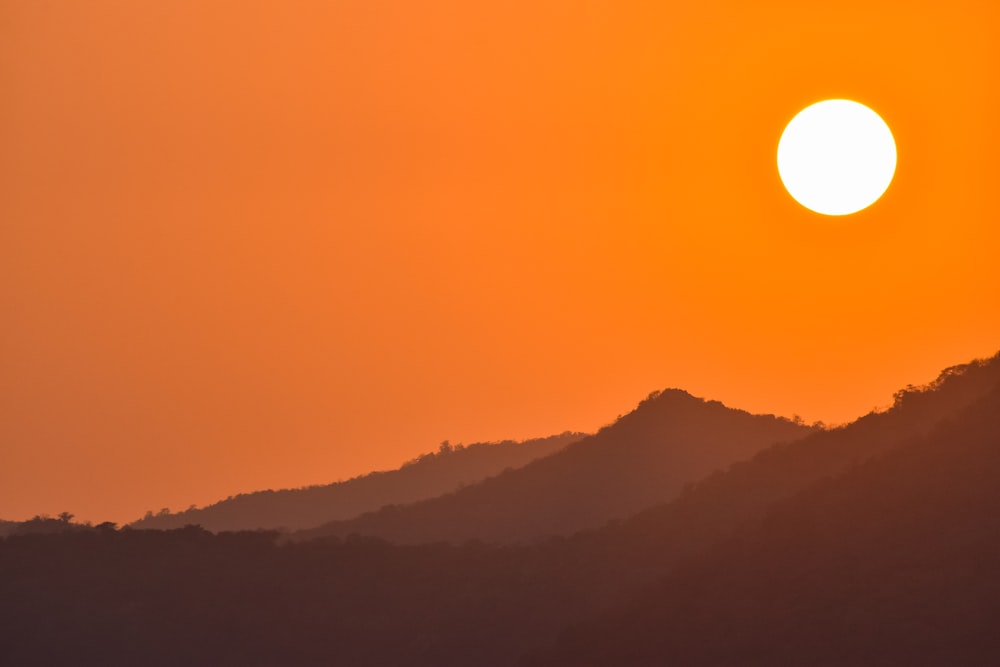 the sun is setting over a mountain range