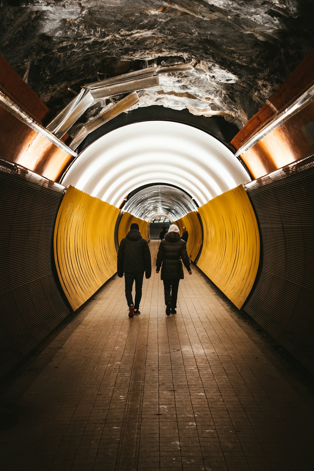 a couple of people that are walking in a tunnel