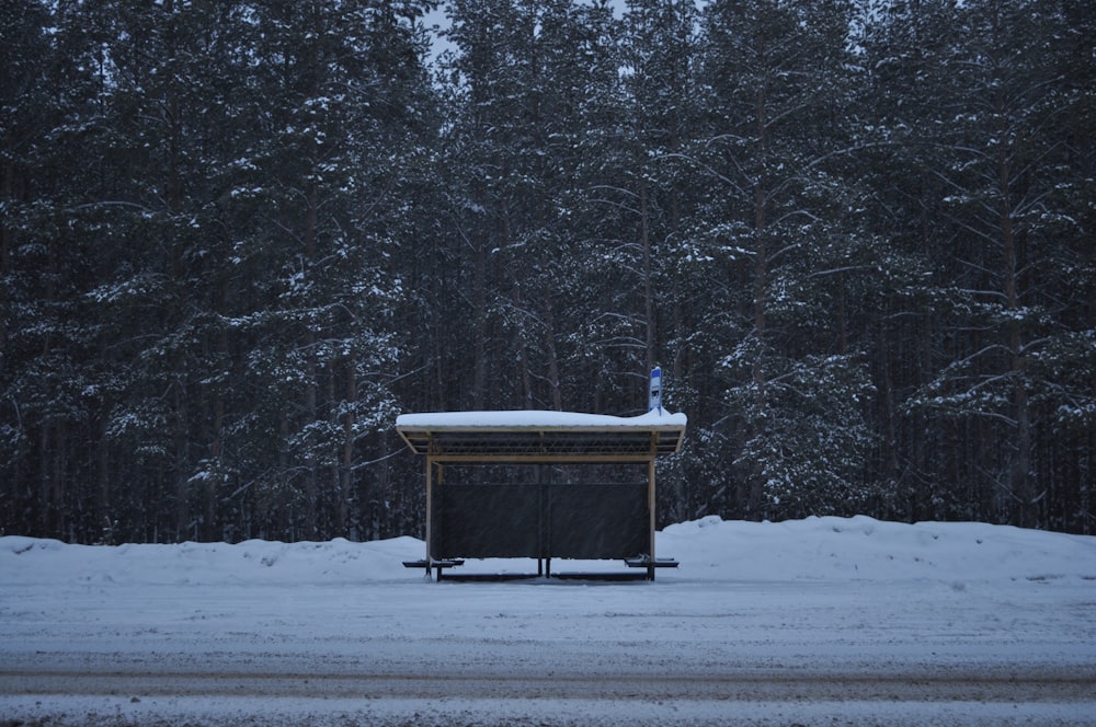 a wooden bench sitting in the middle of a snow covered forest