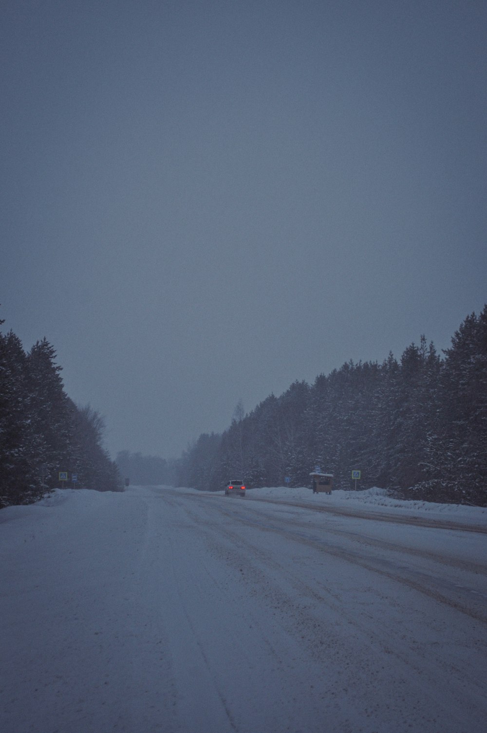 a snow covered road with cars driving on it