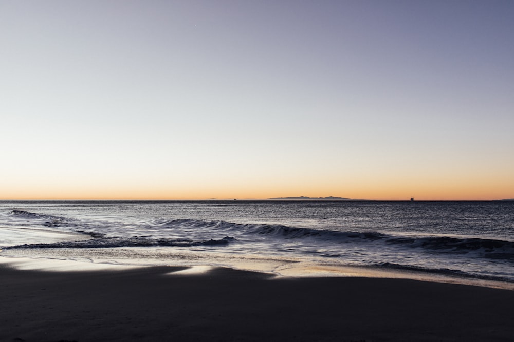 a view of the ocean at sunset with a boat in the distance