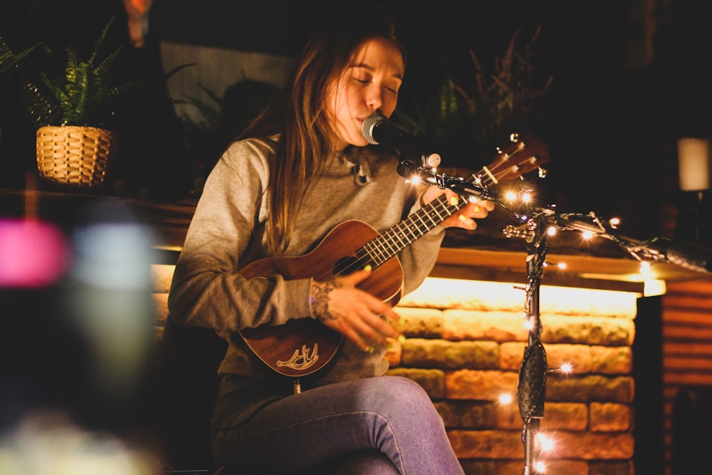 a woman sitting on a bench playing a guitar