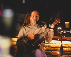 a woman playing a guitar in front of a microphone