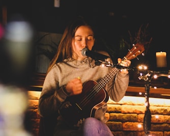a woman playing a guitar in front of a microphone