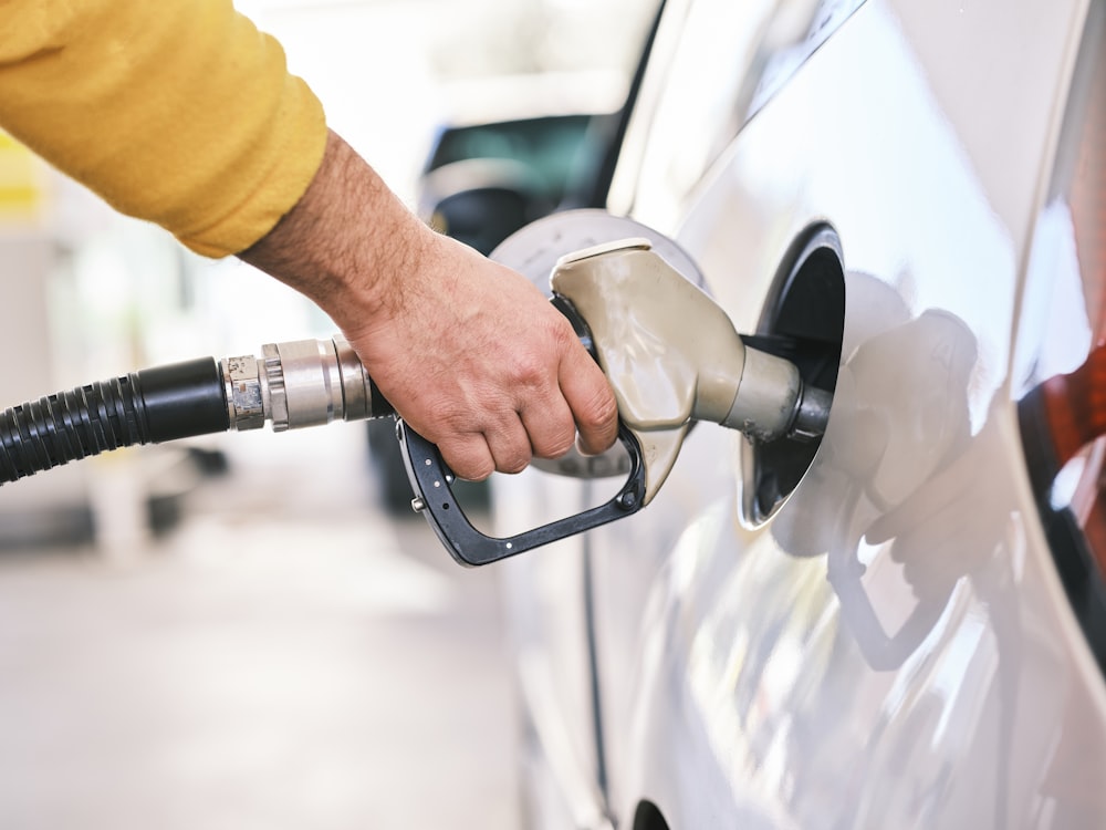 Man in yellow sweatshirt filling up a car with fuel at a gas station