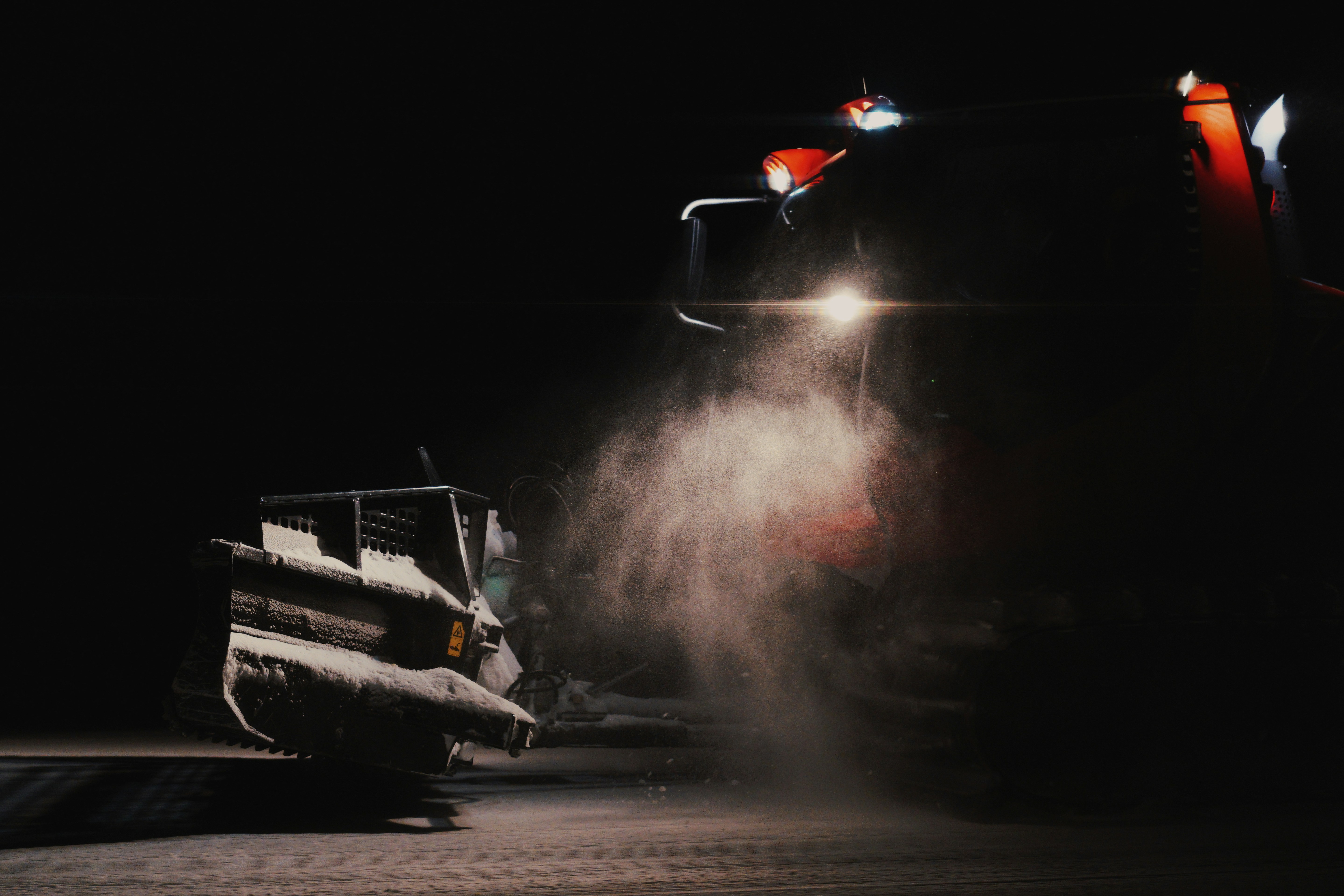 a bulldozer is spraying snow at night