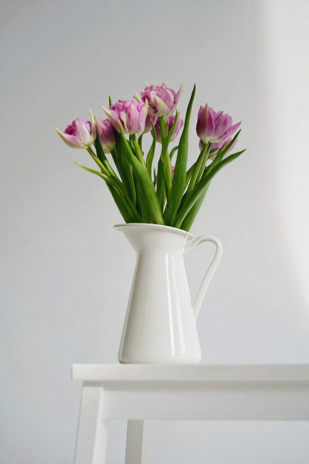 a white vase filled with purple flowers on top of a table